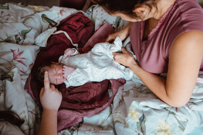 Hand streichelt Frisch geborenes Baby während Mutter es anzieht
