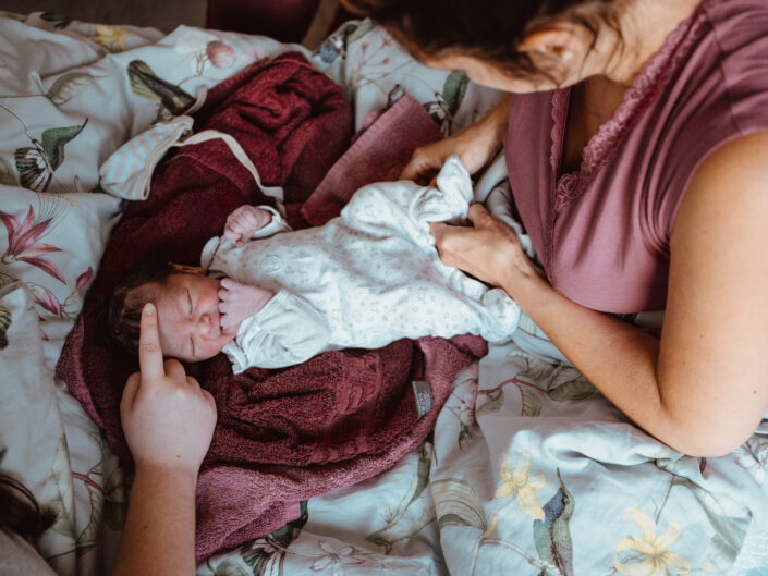 Hand streichelt Frisch geborenes Baby während Mutter es anzieht