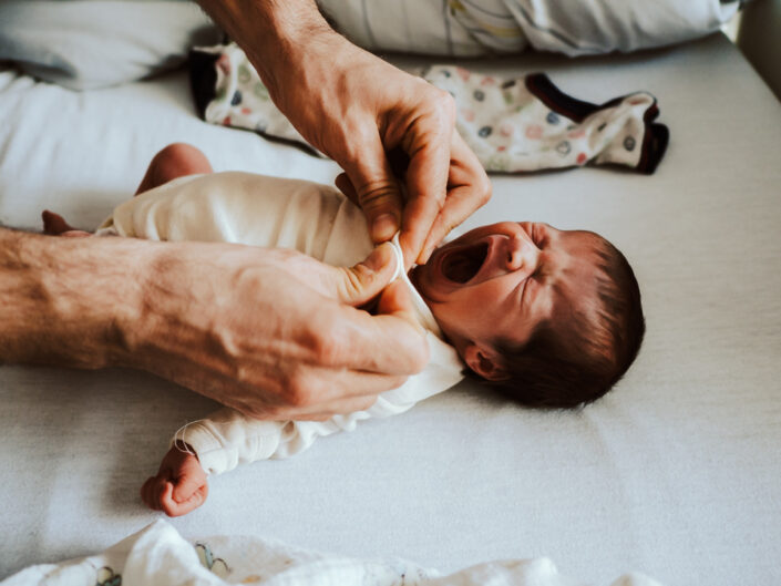 Gähnendes Baby wird angezogen - dokuementarische Babyfotografie