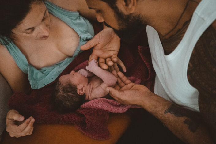 Mutter und Vater bestaunen frisch geborenes Neugeborenes -Geburtsfotos