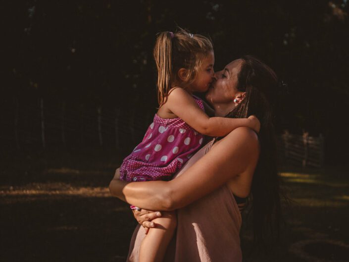 Tochter küsst Mama mit Babybauch