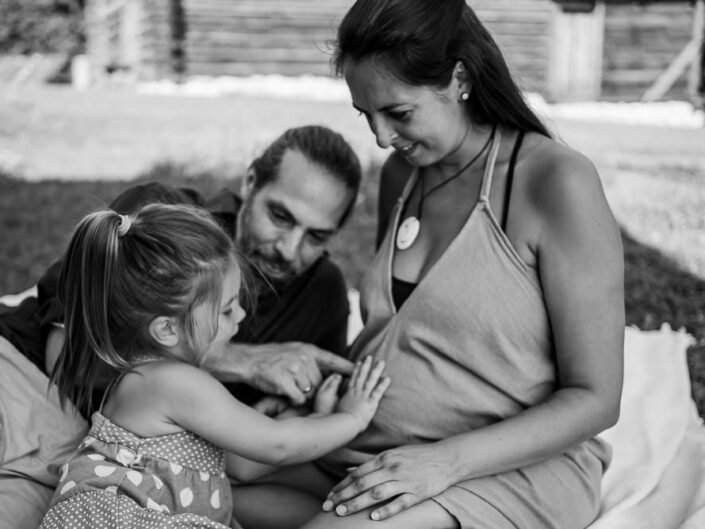 Kind legt Hand auf Babybauch, Familienbild