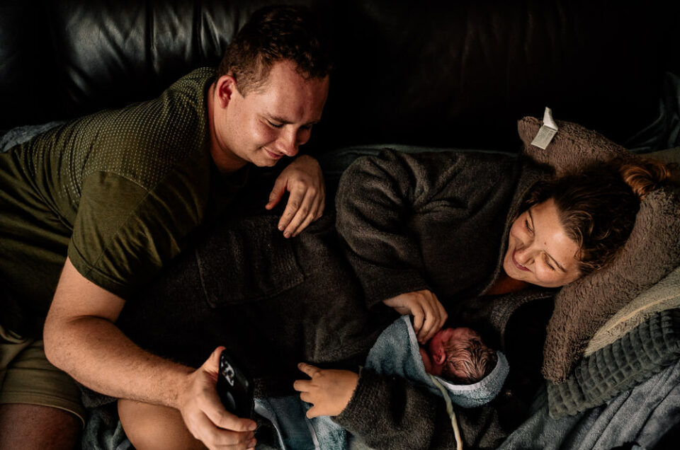 Vater und Mutter zeigen ihr frisch geborenes Baby nach Hausgeburt