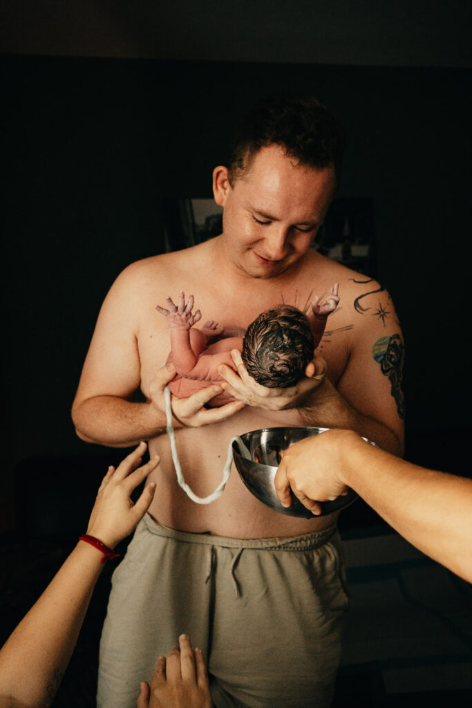 Vater nimmt Baby direkt nach Geburt auf die Arme bei Geburtsreportage
