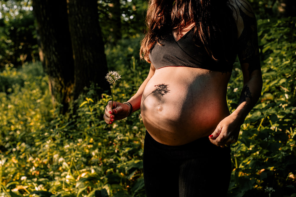 Porträt einer Schwangeren mit Schatten auf dem Bauch im Wald – Emotionen und Natur im Fokus