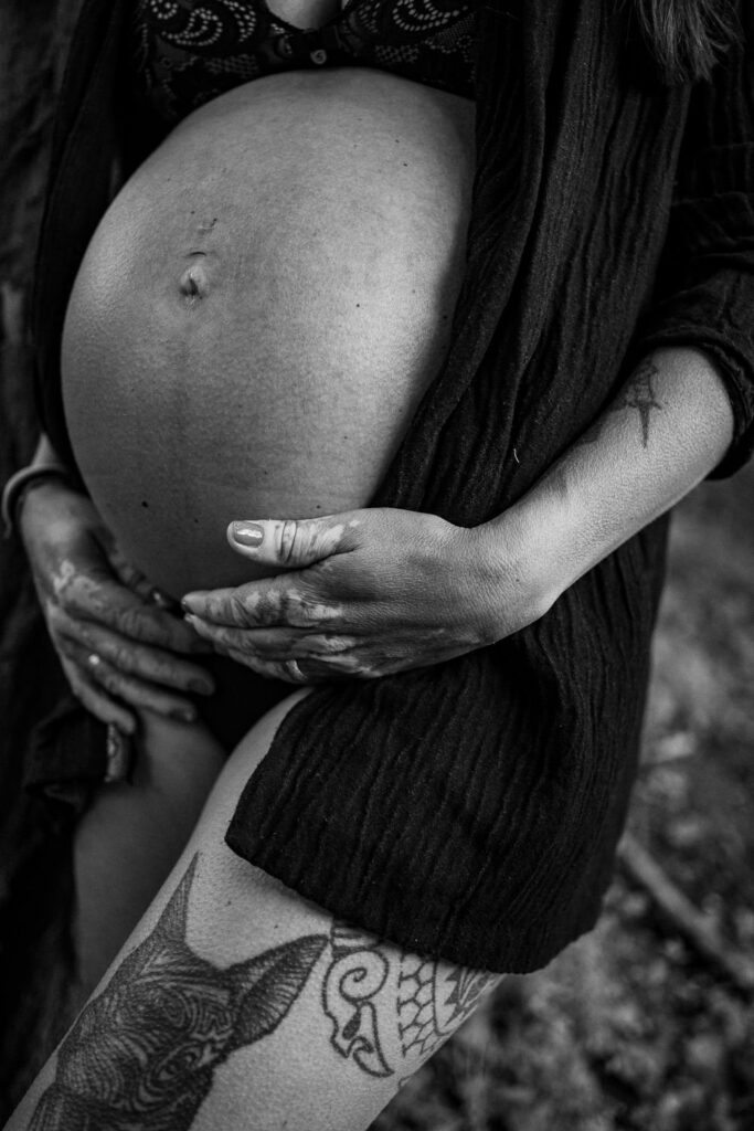 Detailaufnahme von Händen auf einem Babybauch bei natürlichem Licht – Schwangerschaftsfotografie