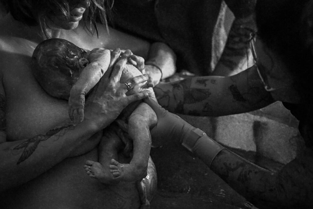 Baby wird in die Arme der Mutter gelegt nach Wassergeburt