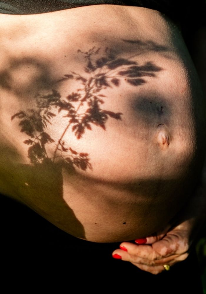 Babybauch mit Schatten auf nackter Haut - natürlich und emotional in der Natur