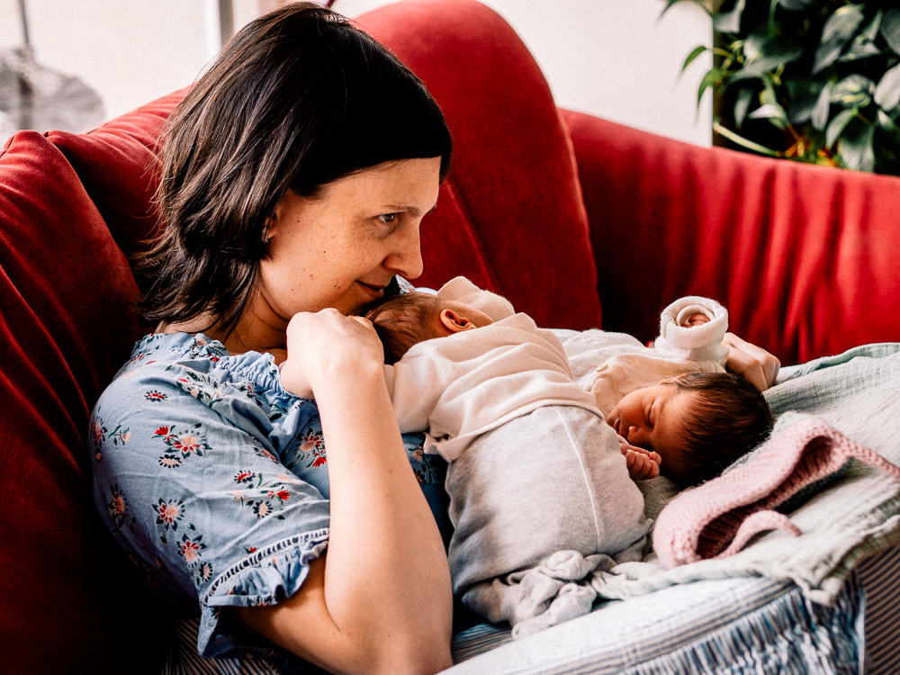 Warum Dokumentarische Familienfotografie so wichtig ist 4 Mutter sitzt mit Baby Zwillingen auf der Couch und genießt den Moment
