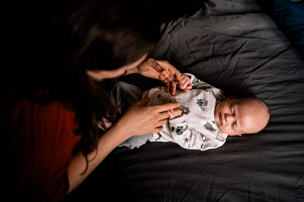 Fotobesuch im Wochenbett 2 Mutter bestaunt Baby im Wochenbett von oben und berührt Hände