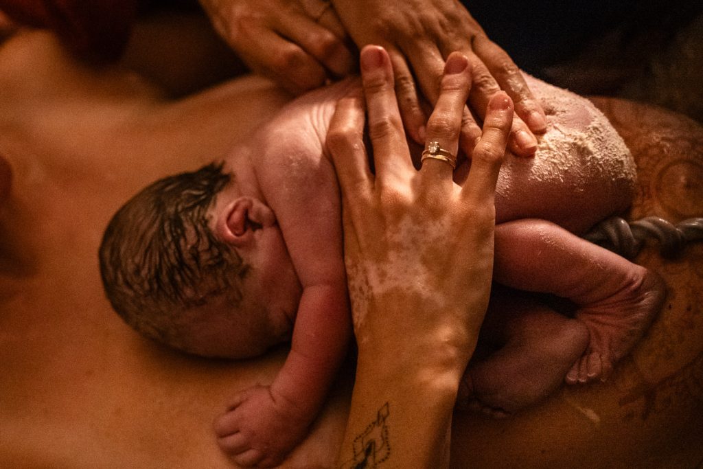 Geburtsfotografie zeigt es - Frisch geboren liegt das Baby voller Käseschmiere am Bauch der Mutter