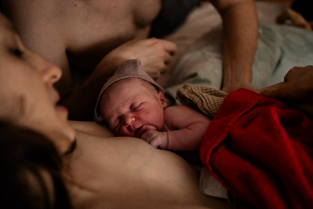 Geburtsreportage endet mit Geburtsfotos von Kuscheln von Baby und Mutter im Bett