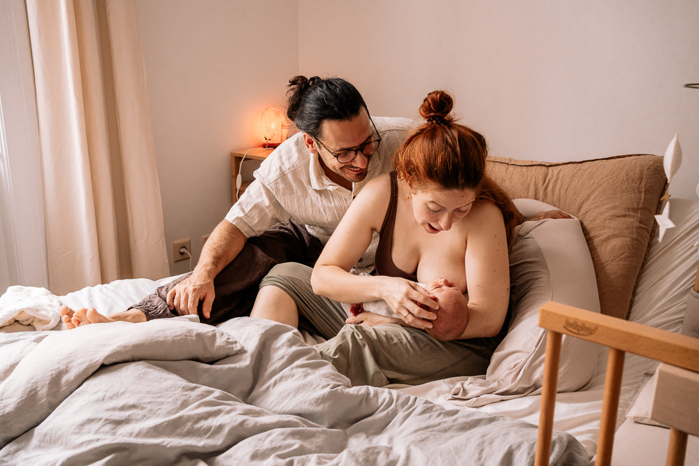 Babyfoto mit Eltern im Wochenbett zuhause Fotoshooting