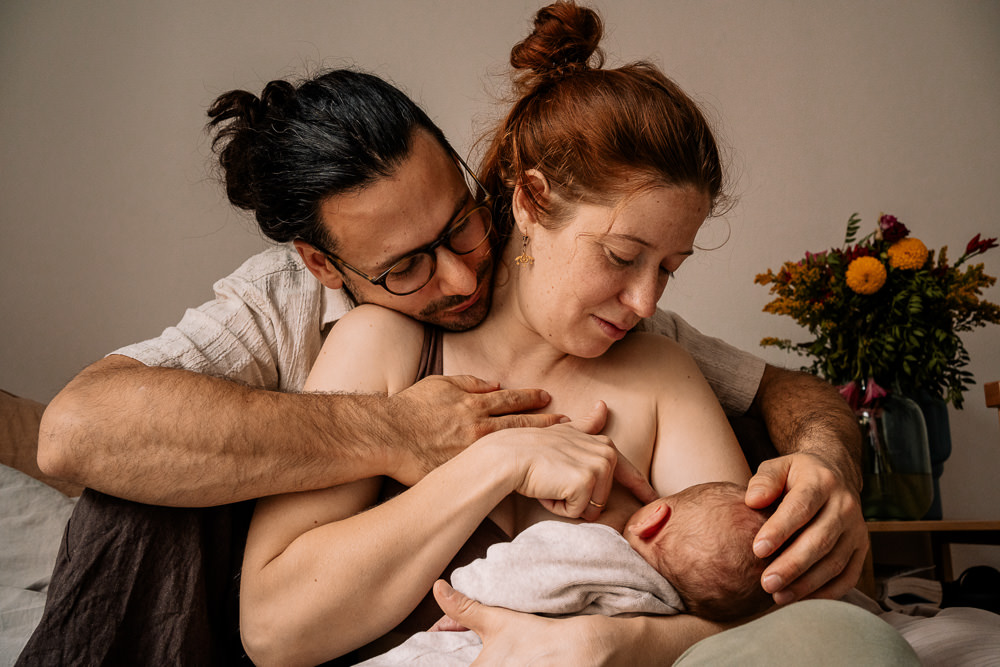 Eltern kuscheln und stillen Neugeborenes beim Wochenbettshooting